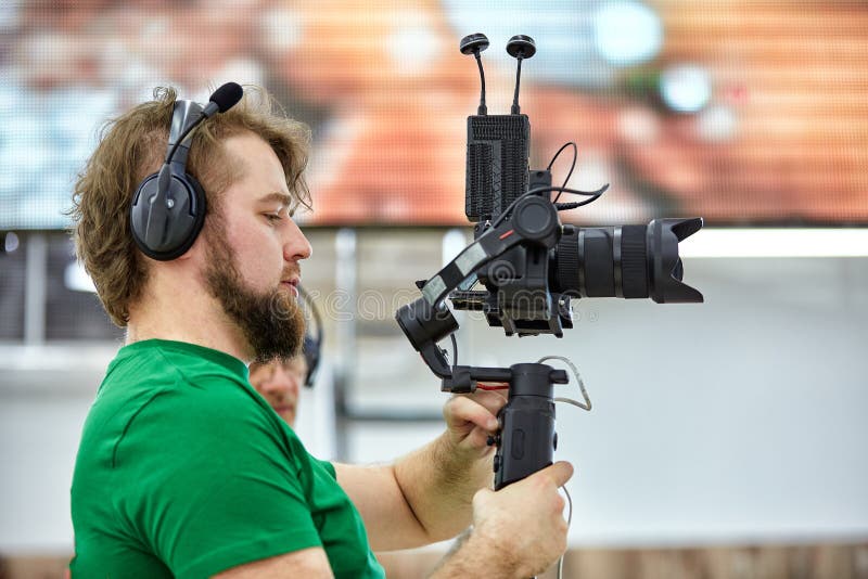 Videographer shooting a film or a television program in a studio with a professional camera, backstage