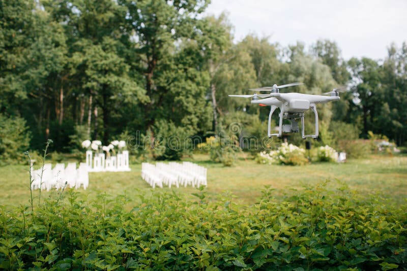 Videographybröllopceremoni från luften en liten spionkvadrathelikopter spanar surrflyg till och med träden i skog arkivbild Videographybröllopceremoni från luften en liten spionkvadrathelikopter spanar surrflyg till och med träden i skog arkivbild