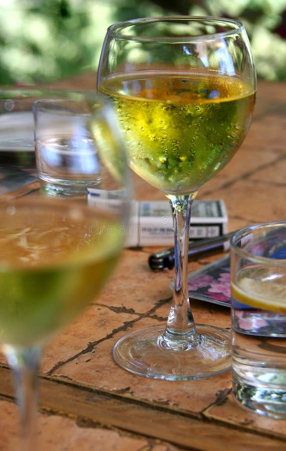 A little table with the glasses filled by white wine, cigarettes and a glass of cold, pure water. A little table with the glasses filled by white wine, cigarettes and a glass of cold, pure water