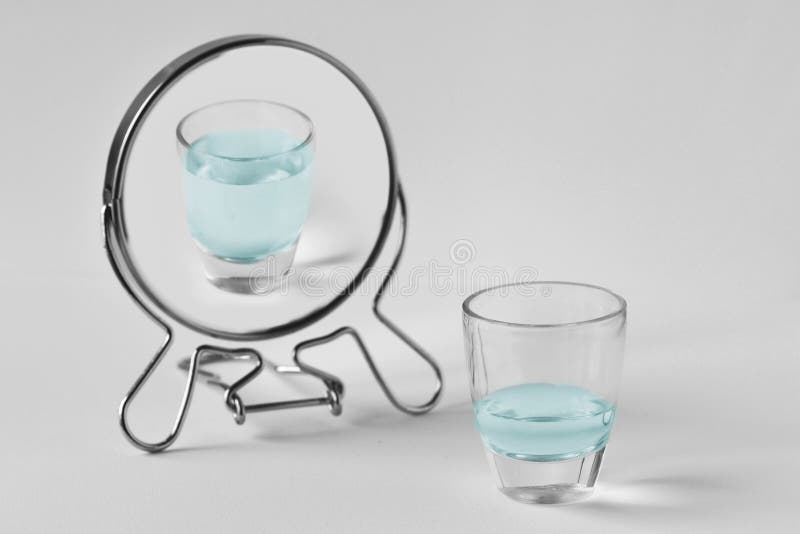 Half-empty water glass looking in the mirror and seeing himself as a full glass. Concept of optimism. Half-empty water glass looking in the mirror and seeing himself as a full glass. Concept of optimism