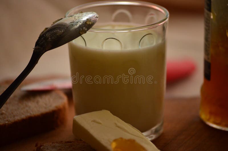 Vidrio de leche fresca, de cuchara con el atasco del albaricoque y de mantequilla foto de archivo Vidrio de leche fresca, de cuchara con el atasco del albaricoque y de mantequilla foto de archivo