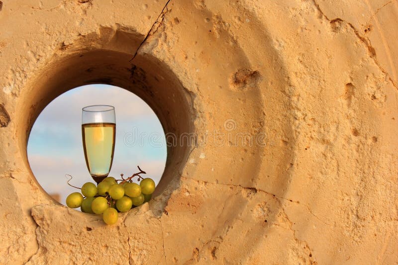 Vidrio de vino blanco y un manojo de uvas dentro de una piedra de molino imágenes de archivo libres de regalías Vidrio de vino blanco y un manojo de uvas dentro de una piedra de molino imágenes de archivo libres de regalías