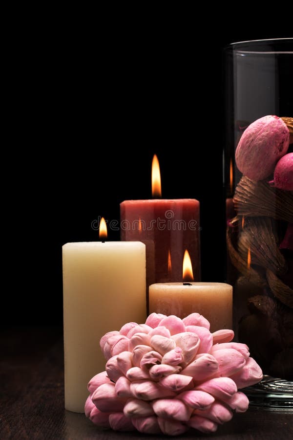 Vidrio llenado de popurrí marrón, rosado y rojo con tres velas encendidas en la tabla de madera con el fondo negro Iluminación de fotografía de archivo libre de regalías Vidrio llenado de popurrí marrón, rosado y rojo con tres velas encendidas en la tabla de madera con el fondo negro Iluminación de fotografía de archivo libre de regalías