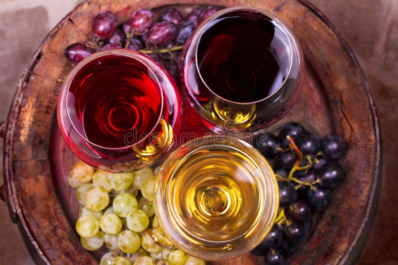 Vidrios de vino blanco del rojo, color de rosa y con la uva en bodega Comida y concepto de las bebidas imágenes de archivo libres de regalías Vidrios de vino blanco del rojo, color de rosa y con la uva en bodega Comida y concepto de las bebidas imágenes de archivo libres de regalías
