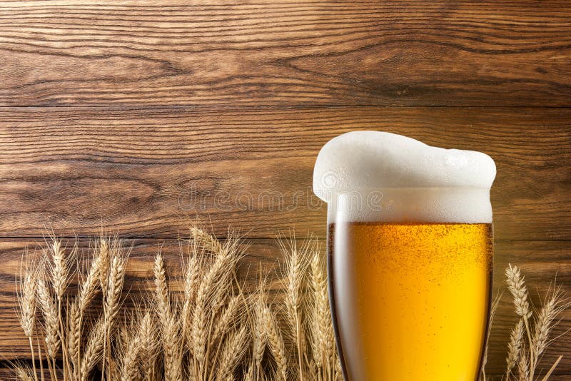 Glass of beer with wheat on wooden background. Glass of beer with wheat on wooden background