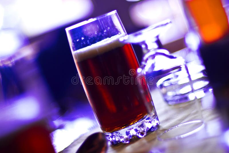 A glass of dark beer on a bar. A glass of dark beer on a bar.