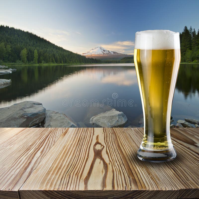 Glass of cold beer on wood table with nature scene background. Glass of cold beer on wood table with nature scene background