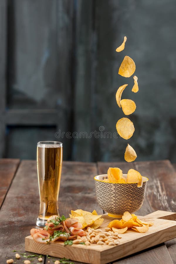 Vidro de cerveja e microplaquetas de batata, pistaches em um branco imagens de stock royalty free Vidro de cerveja e microplaquetas de batata, pistaches em um branco imagens de stock royalty free