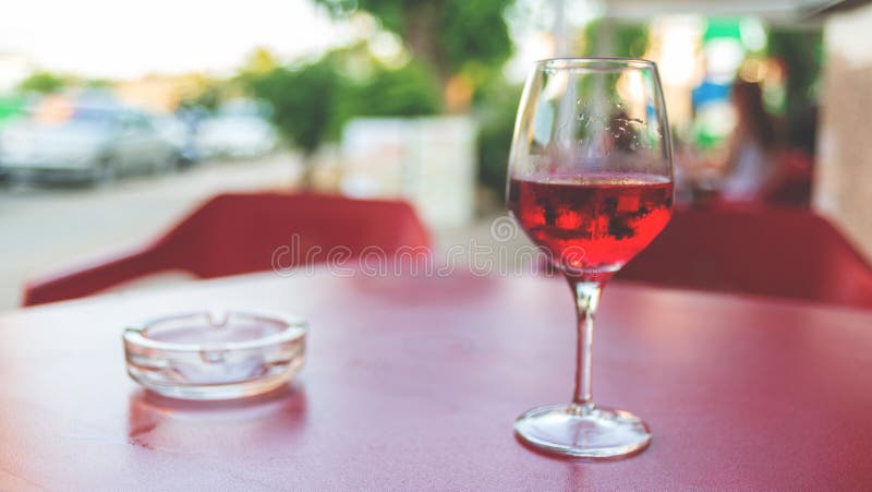 Vidro do vinho cor-de-rosa na tabela em tonificação Defocused do vintage da imagem do café da rua fotografia de stock Vidro do vinho cor-de-rosa na tabela em tonificação Defocused do vintage da imagem do café da rua fotografia de stock