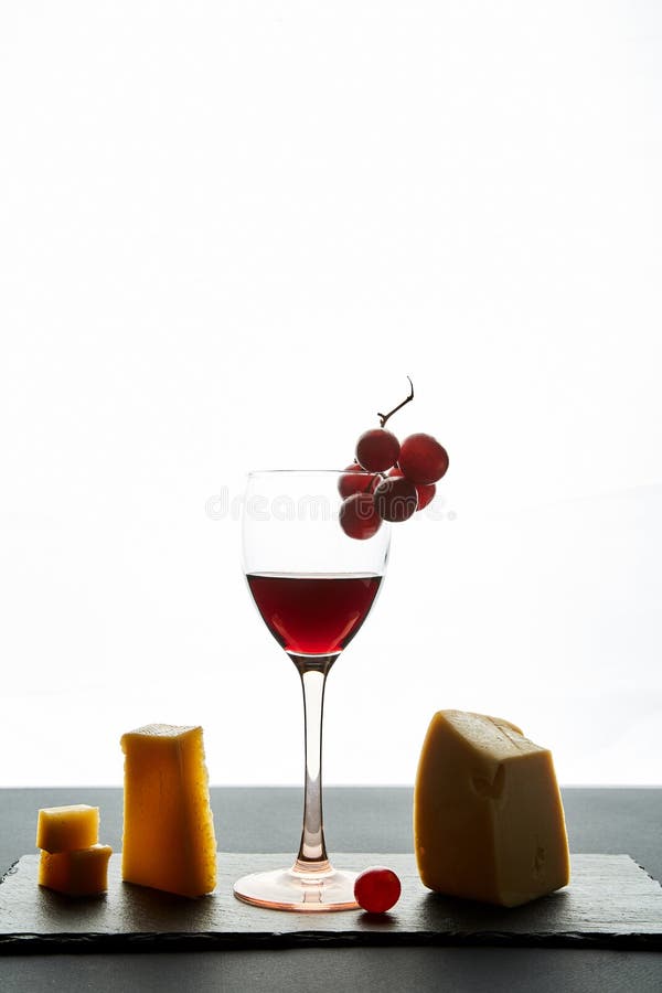 Vidro do vinho tinto decorado com uva e tipos diferentes do queijo imagem de stock royalty free Vidro do vinho tinto decorado com uva e tipos diferentes do queijo imagem de stock royalty free