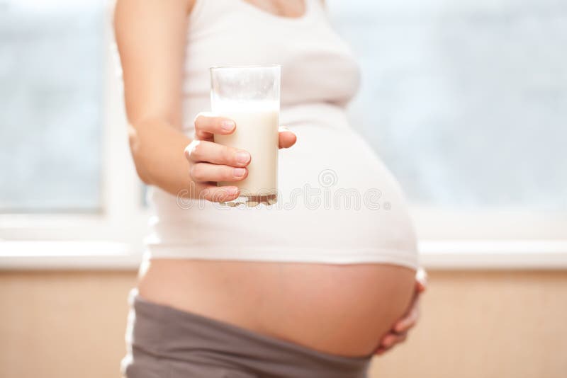Grávida com um copo de leite fotografia de stock royalty free