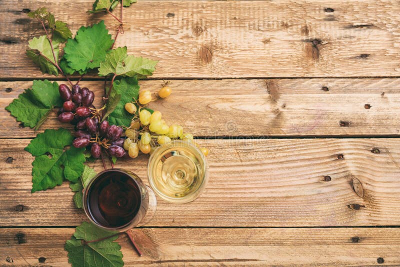 Vidros de vinho vermelho e branco e uvas frescas no fundo de madeira, espaço da cópia imagens de stock Vidros de vinho vermelho e branco e uvas frescas no fundo de madeira, espaço da cópia imagens de stock