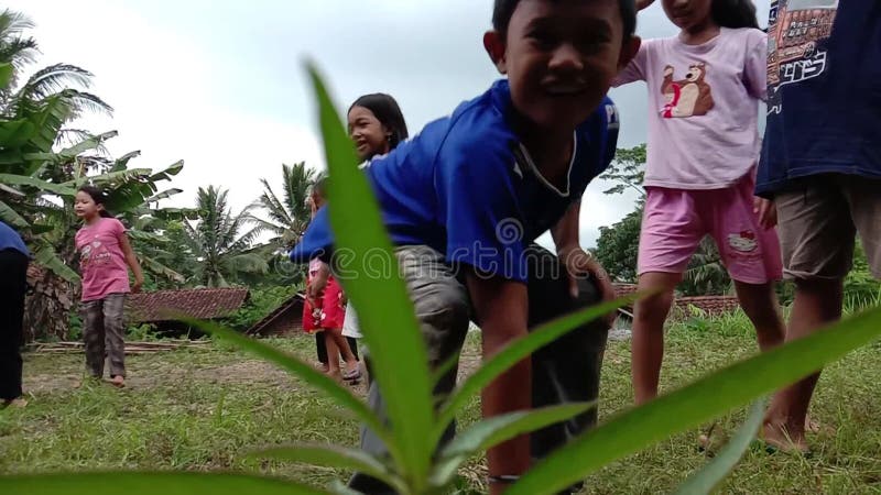 Vidéo d'un groupe d'enfants asiatiques qui jouent dans un champ ils ont l'air heureux