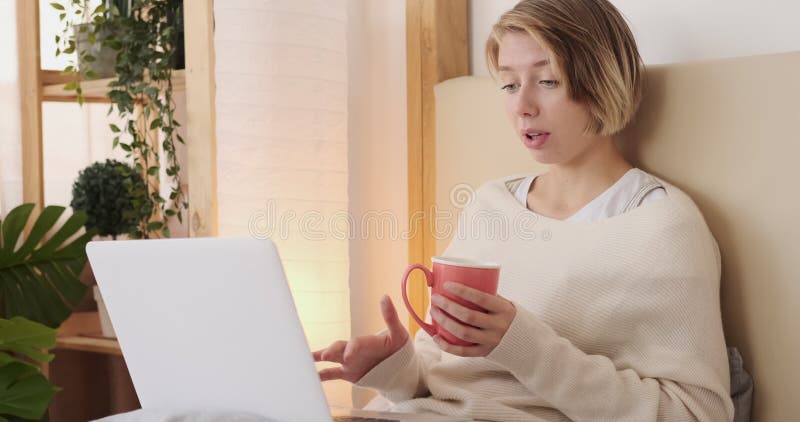 Vidéo d'une femme appelant à l'aide d'un ordinateur portable assis sur son lit banque de vidéos