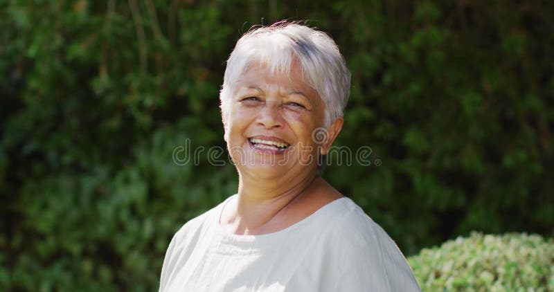 Vidéo d'une femme senior biraciale heureuse regardant la caméra dans le jardin clips vidéos
