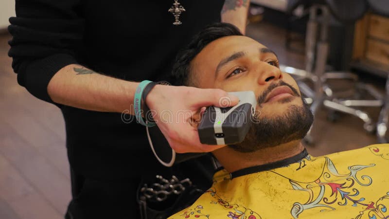 Vidéo de clôture d'un client de salons de coiffeur allongé sur une chaise en ayant sa barbe et ses cheveux cheek coupés banque de vidéos