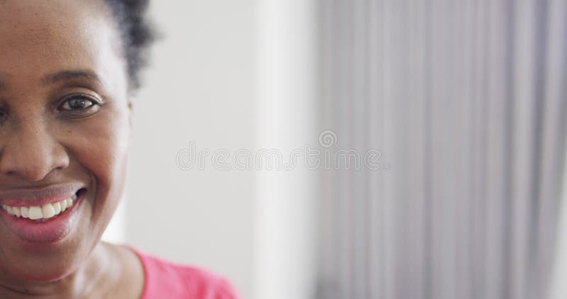 Vidéo demi-visage portrait d'une femme afro-américaine heureuse riant devant la caméra à la maison avec espace photographique banque de vidéos