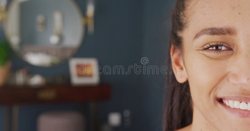 Vidéo demi-visage portrait d'une femme biraciale heureuse à la maison sourire à la caméra avec espace de copie banque de vidéos