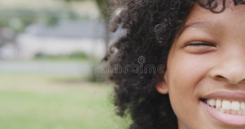 Vidéo demi-visage portrait d'écolière biraciale souriante à l'école terrain de jeu avec espace de copie clips vidéos