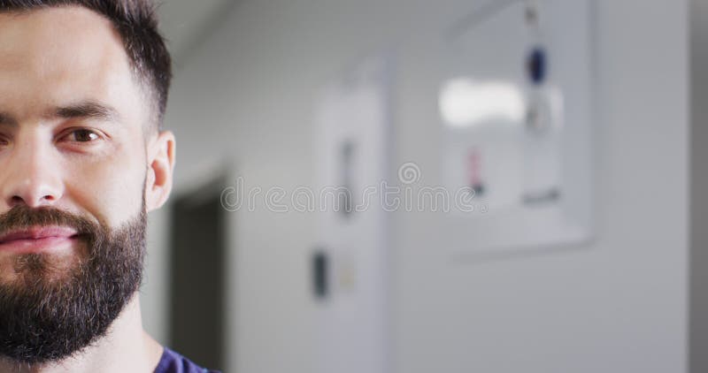 Vidéo demi-visage portrait de caucasien barbu souriant travailleur médical dans l'espace de copie de couloir banque de vidéos