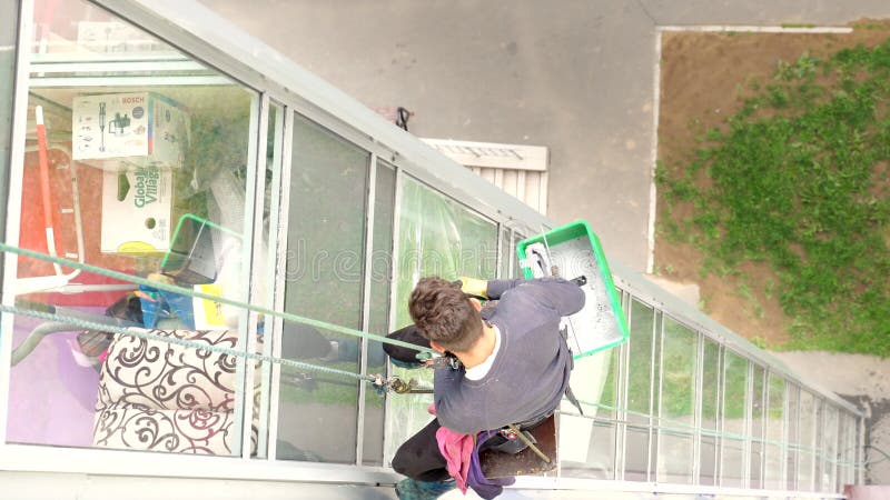 Vidéo des fenêtres de lavage d'homme mountaineer dans le bâtiment à plusieurs étages. Profession dangereuse. Jeunes vêtements de t clips vidéos