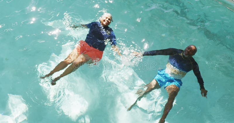 Vidéo verticale d'un couple africain senior américain heureux faisant de l'exercice dans la piscine banque de vidéos