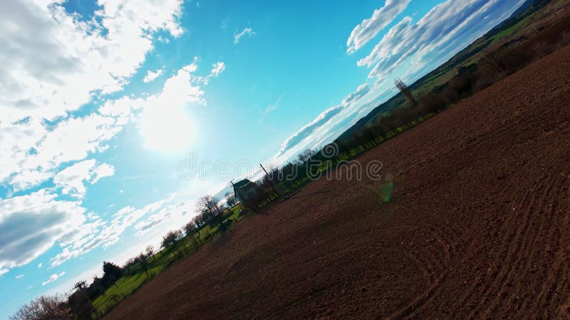 Vidéo verticale FPV drone vue banque sur des champs verts vibrants et campagne ondulante sous ciel bleu vif avec clips vidéos