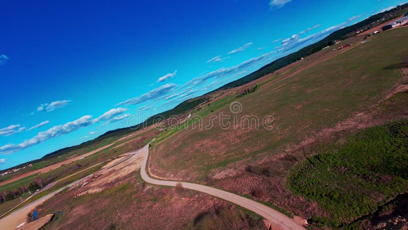 Vidéo verticale FPV drone vue banque sur des champs verts vibrants et campagne ondulante sous ciel bleu vif avec banque de vidéos