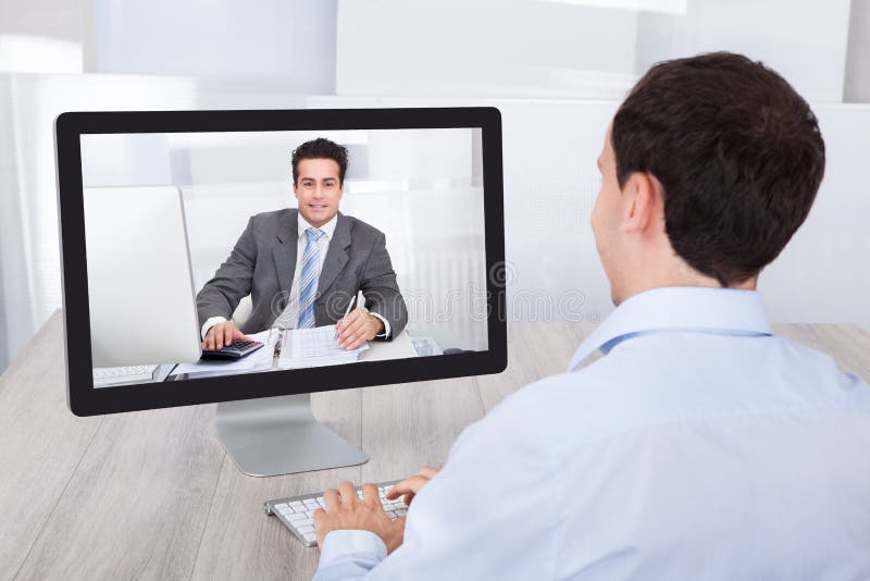 Vidéoconférence d'homme d'affaires avec le collègue sur le PC au bureau images stock Vidéoconférence d'homme d'affaires avec le collègue sur le PC au bureau images stock
