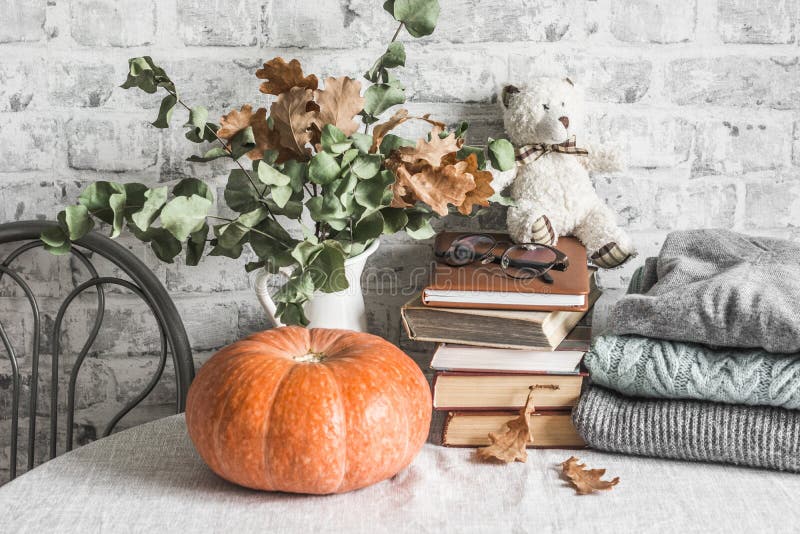 Vie de maison confortable d'automne citrouille, lanceur de branches sèches, pile de livres, pile de pulls d'automne d'hiver, ours photographie stock libre de droits Vie de maison confortable d'automne citrouille, lanceur de branches sèches, pile de livres, pile de pulls d'automne d'hiver, ours photographie stock libre de droits