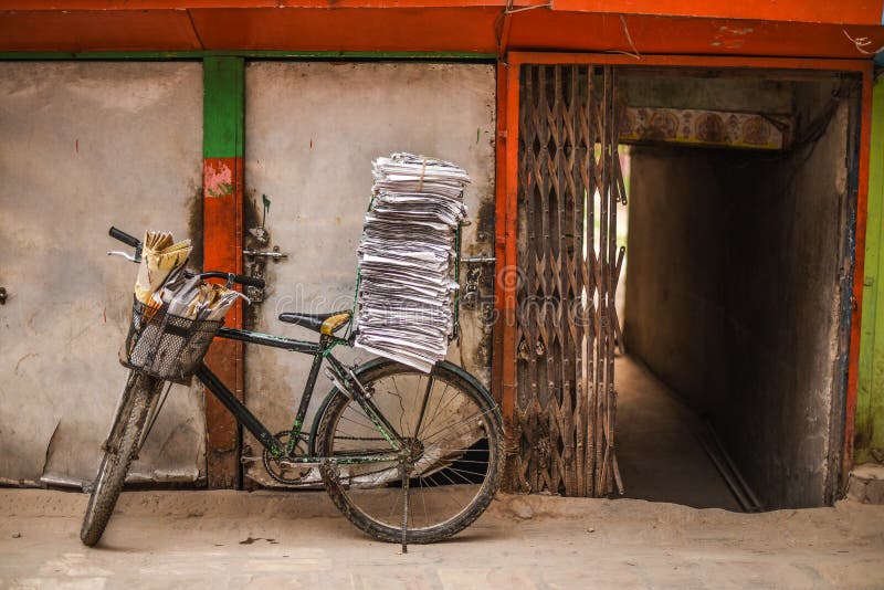 Vieille bicyclette avec la pile de journaux près de mur rustique photographie stock libre de droits Vieille bicyclette avec la pile de journaux près de mur rustique photographie stock libre de droits