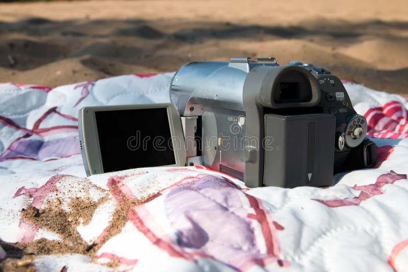 Vieille caméra vidéo sur la plage, sur un couvre-lit coloré, sur le sable image stock Vieille caméra vidéo sur la plage, sur un couvre-lit coloré, sur le sable image stock