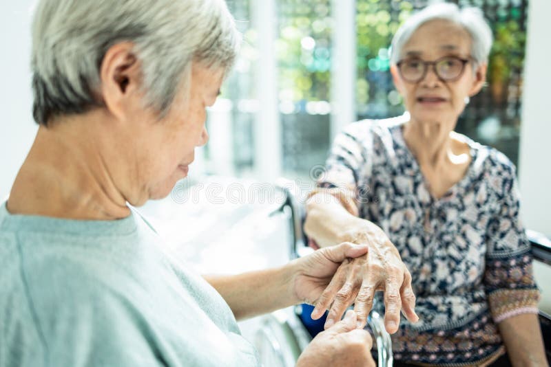 Asian elderly women massaging palm and fingers of friend senior or sister having heumatoid arthritis, beriberi,peripheral neuropathies,old people suffer from hand numbness,muscle pain,sore,achy hand. Asian elderly women massaging palm and fingers of friend senior or sister having heumatoid arthritis, beriberi,peripheral neuropathies,old people suffer from hand numbness,muscle pain,sore,achy hand