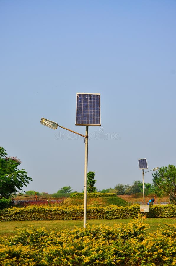 Old solar lamp pole in the garden with green vegetation and blue sky at the background. Old solar lamp pole in the garden with green vegetation and blue sky at the background