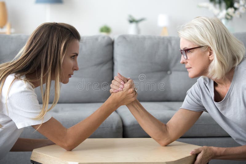 Vieille mère et bras de fer développé de fille ayant le combat de famille photographie stock libre de droits Vieille mère et bras de fer développé de fille ayant le combat de famille photographie stock libre de droits