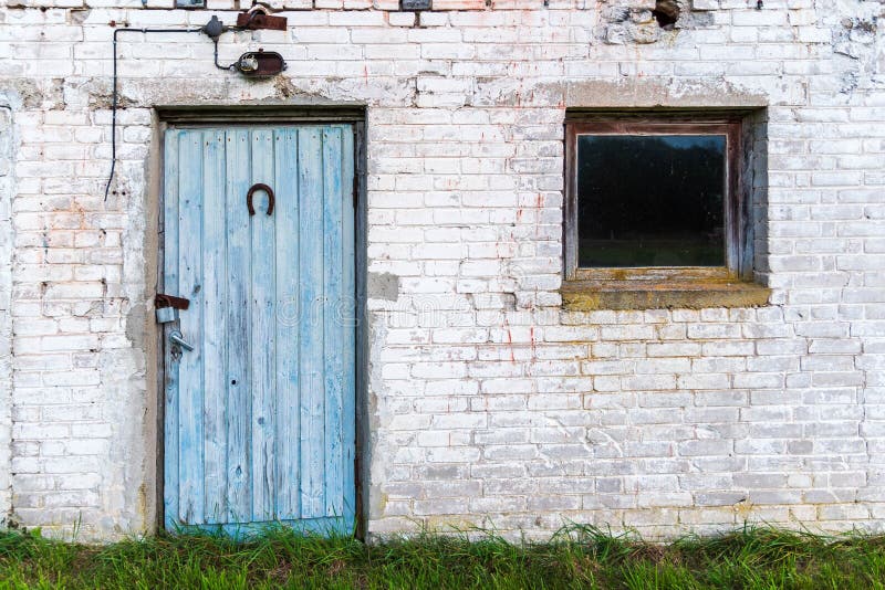 Vieille porte bleue et petite fenêtre d'une grange de Soviétique-ère image stock Vieille porte bleue et petite fenêtre d'une grange de Soviétique-ère image stock