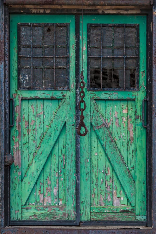 Old double green wooden warehouse door with a crane hook in front. Old double green wooden warehouse door with a crane hook in front