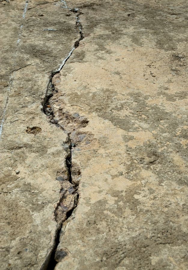 An old road neglected and in disrepair with a large crack developing. An old road neglected and in disrepair with a large crack developing
