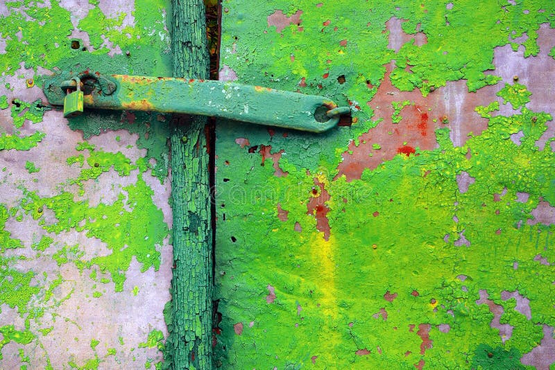 Detail of a old metallic door with peeling green paint and padlock. Detail of a old metallic door with peeling green paint and padlock