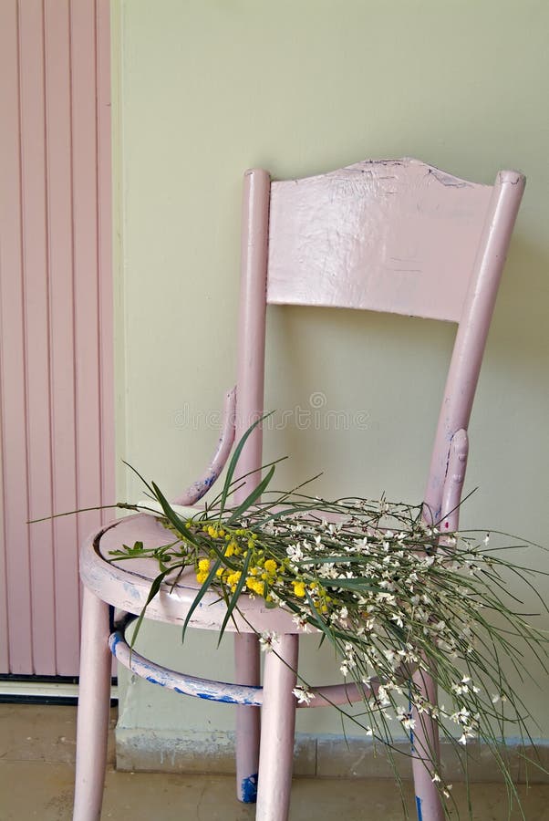 Old pink chair and flowers in front of green wall and pink door. Old pink chair and flowers in front of green wall and pink door.