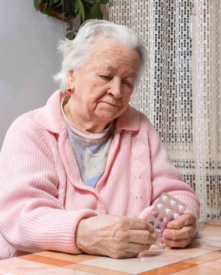 Vieja mujer triste que sostiene píldoras fotografía de archivo libre de regalías Vieja mujer triste que sostiene píldoras fotografía de archivo libre de regalías