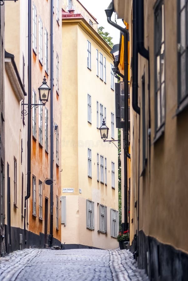 Wonderful photo (quite positive and calm view; vertical landscape) of The Old Tallin's street: ancient buildings with ascetic and in the same time elegant design, matt one color surfaces of the walls, wooden square windows with cells, old streetlights and black pipes, ancient cobblestones, etc. Image is also can be related with a topic of migration to Europe for better life. For different purposes (design, architecture, cultural, historical topics, good for postcard, etc.). Wonderful photo (quite positive and calm view; vertical landscape) of The Old Tallin's street: ancient buildings with ascetic and in the same time elegant design, matt one color surfaces of the walls, wooden square windows with cells, old streetlights and black pipes, ancient cobblestones, etc. Image is also can be related with a topic of migration to Europe for better life. For different purposes (design, architecture, cultural, historical topics, good for postcard, etc.).