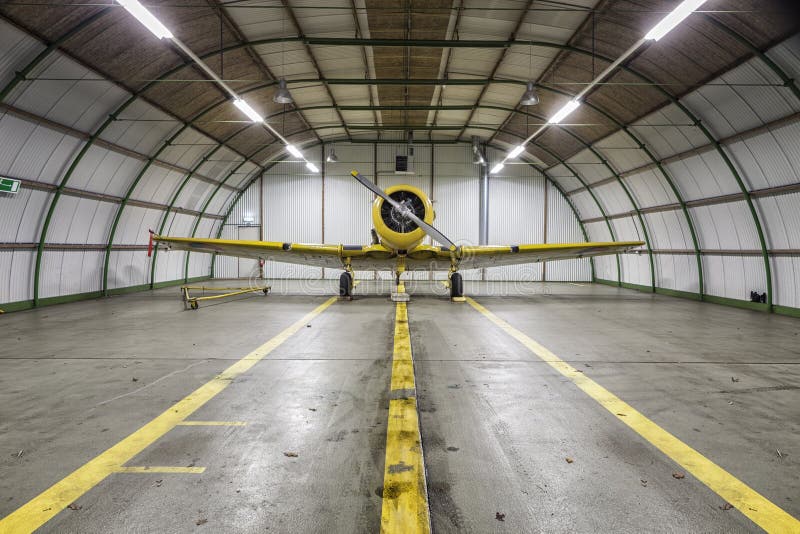 Viejo avión amarillo de la guerra del vintage dentro de un hangar vacío fotografía de archivo libre de regalías Viejo avión amarillo de la guerra del vintage dentro de un hangar vacío fotografía de archivo libre de regalías