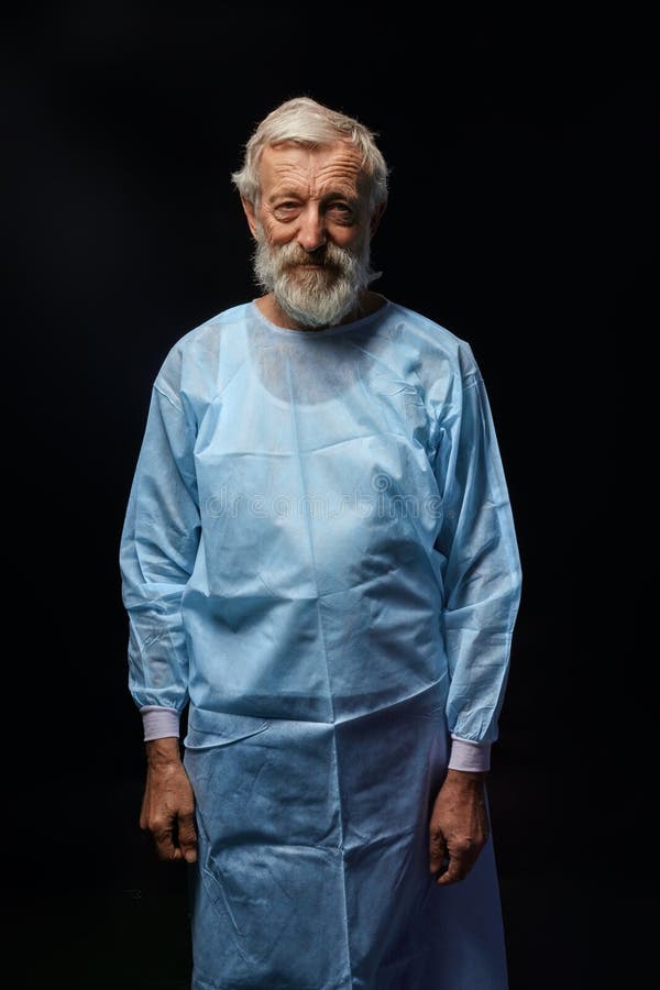 Viejo doctor hermoso en el uniforme especial que presenta a la cámara imágenes de archivo libres de regalías Viejo doctor hermoso en el uniforme especial que presenta a la cámara imágenes de archivo libres de regalías