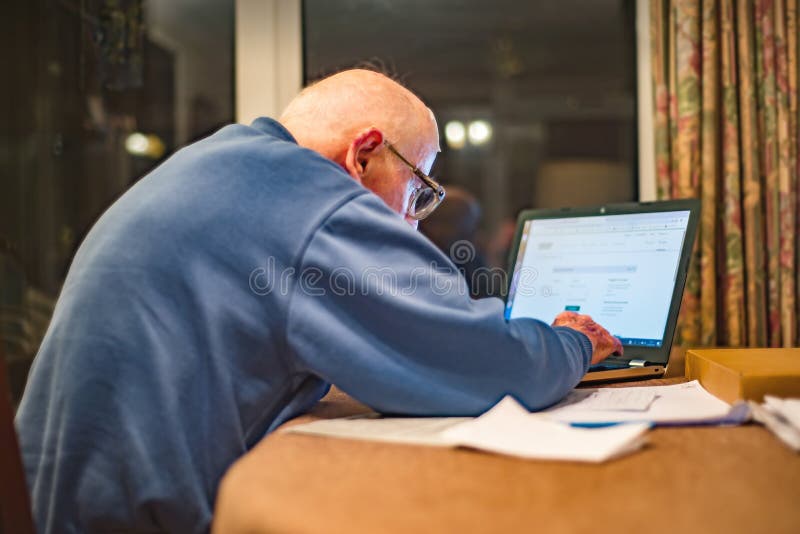 Viejo Hombre Un Ordenador Portátil Para Comprobar Sus Carteras De Participaciones, Hampshire, Inglaterra, U Foto de - de ayuda, internet: 147661124
