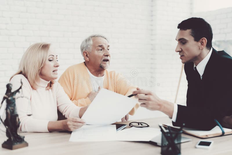 Viejo hombre y mujer que visitan al abogado joven en oficina imagen de archivo libre de regalías