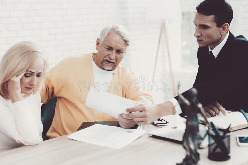 Viejo hombre y mujer que visitan al abogado joven en oficina fotografía de archivo