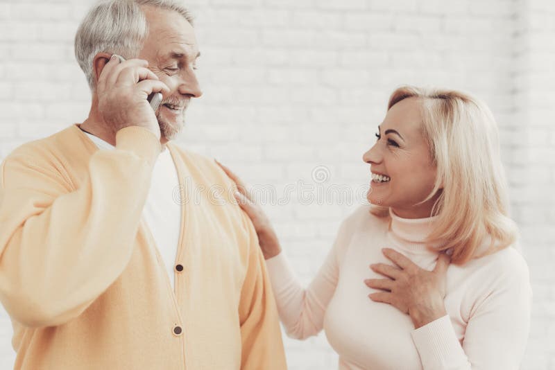 Viejo hombre y mujer sonrientes que hablan en Smartphone imágenes de archivo libres de regalías