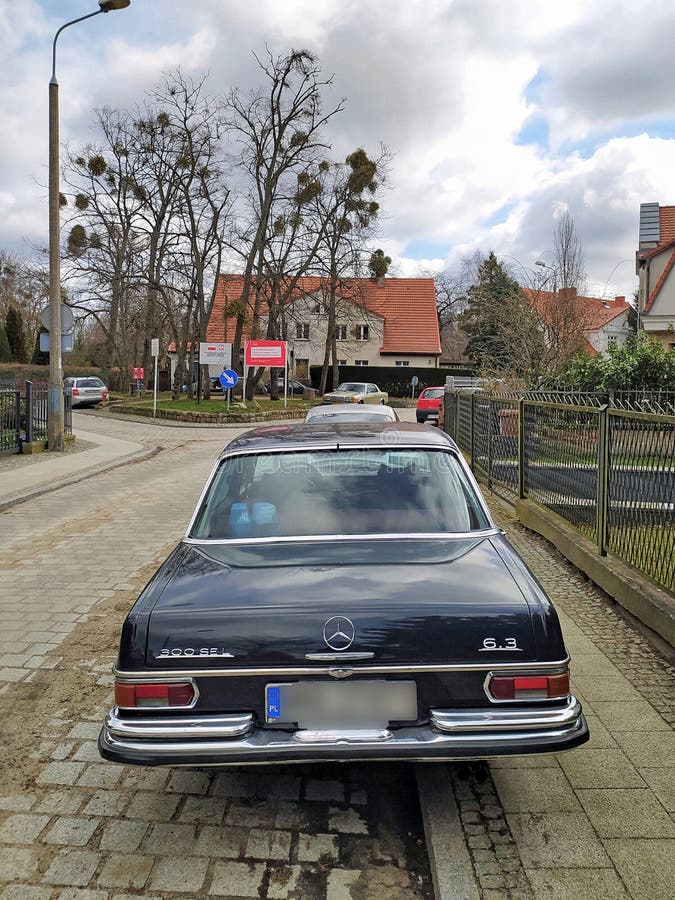 Old vintage classic black extremely rare veteran luxury historic model of black chromed luxury performance sports sedan muscle car Mercedes Benz 300 SEL 6.3 lite V8 engine parked in old district in Gdansk Wrzeszcz in northern Poland. Old houses and huge trees in the background. Rear part view with logo and model number. Expensive and rare four-door muscle performace automobile produced between 1968 and 1972. Old vintage classic black extremely rare veteran luxury historic model of black chromed luxury performance sports sedan muscle car Mercedes Benz 300 SEL 6.3 lite V8 engine parked in old district in Gdansk Wrzeszcz in northern Poland. Old houses and huge trees in the background. Rear part view with logo and model number. Expensive and rare four-door muscle performace automobile produced between 1968 and 1972.