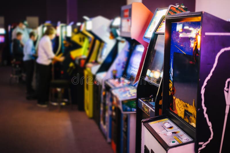 Viejo vintage Arcade Games en un cuarto oscuro y jugadores que juegan en el fondo